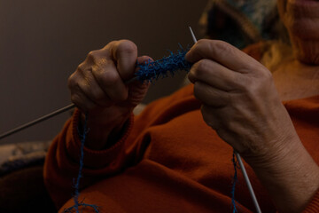 older woman's hands knitting small patch of blue fabric