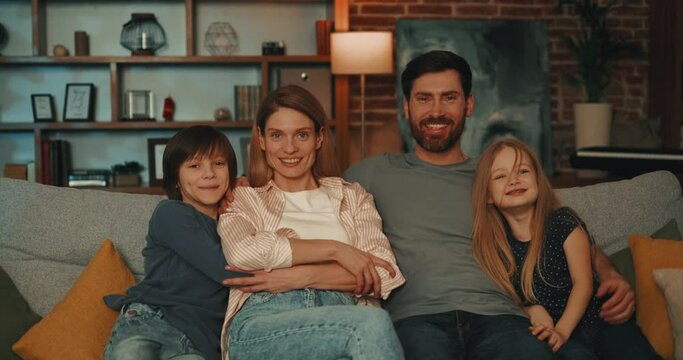 Portrait of  Ukrainian family with kids relaxing on sofa and looking at camera