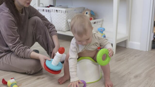 Mother training her baby to sit on the potty 1 year old infant seem interested in using the toilet. High quality 4k footage