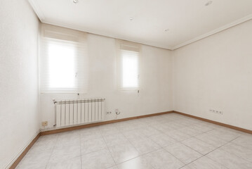 Empty room with light stoneware floor, oak baseboards, aluminum radiators, windows with translucent blinds and plaster molding on the ceiling