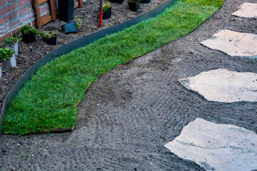 Making of natural green lawn in garden with rolls of green grass, garden works in spring