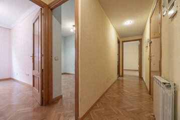 Distributor corridor of a house with oak carpentry, matching herringbone parquet, aluminum radiators and walls in need of a coat of paint