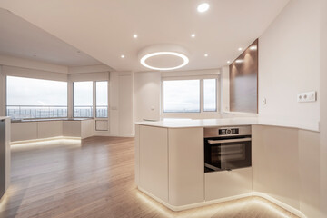 One story kitchen with white wood cabinets with white stone top in a study with large windows and oak parquet flooring