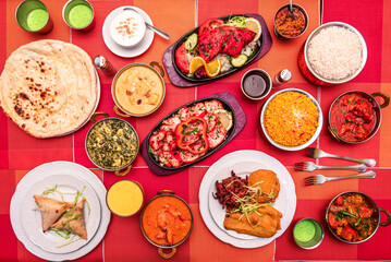 Colorful Indian food plates with various types of curries, naan, palak paneer, lamb, tandoori chicken, tikka masala, appetizers, basmati rice, falafel, pilau rice and many assorted spices
