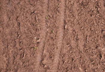 Trilhos das rodas de um trator marcados na terra de um campo lavrado
