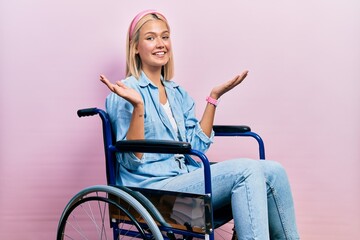 Beautiful blonde woman sitting on wheelchair smiling showing both hands open palms, presenting and advertising comparison and balance