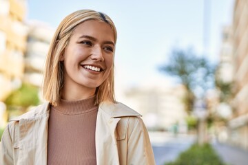 Young blonde girl smiling happy standing at the city.