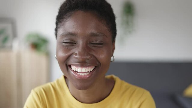 Young pretty black woman smiling at camera while standing at home - Happy people concept