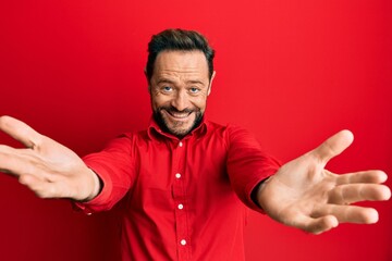 Middle age man wearing casual clothes looking at the camera smiling with open arms for hug. cheerful expression embracing happiness.