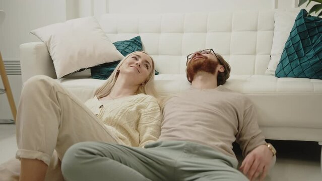 content caucasian couple celebrating Women's Day laying on the floor, looking up, and smiling. High quality 4k footage