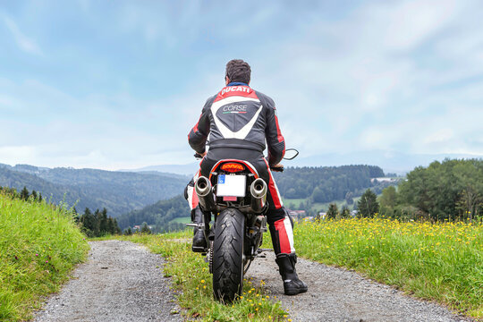 Grafenau, Bavaria, Germany, 2021, August 18th: A biker drives his ducati monster motorbike on a rural dirt road offroads in front of a beautiful landscape