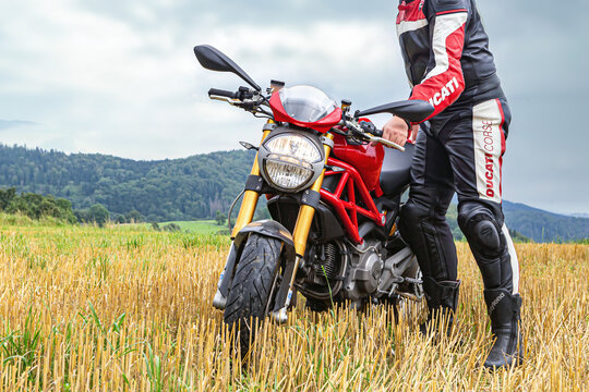 Grafenau, Bavaria, Germany, 2021, August 18th: A biker drives his ducati monster motorbike on a rural dirt road offroads in front of a beautiful landscape