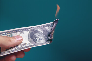 hand holds a dollar bill that is burning