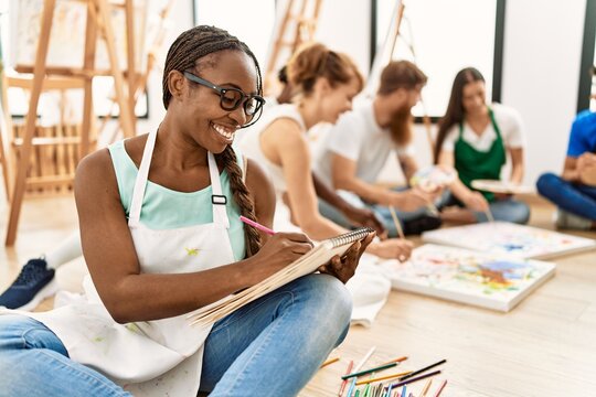 Group of people smiling happy drawing sitting on the floor at art studio.