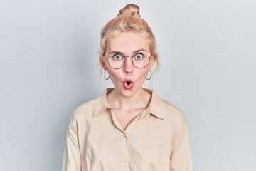 Beautiful caucasian woman with blond hair wearing casual look and glasses afraid and shocked with surprise expression, fear and excited face.