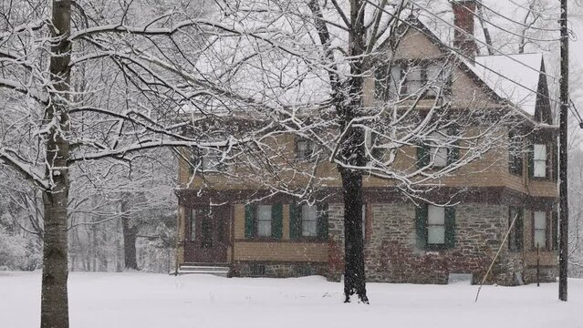 Snow falling in slow motion in front of historic American house in winter