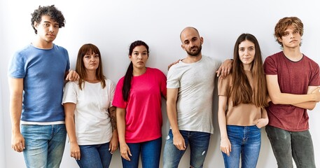 Group of young friends standing together over isolated background relaxed with serious expression on face. simple and natural looking at the camera.