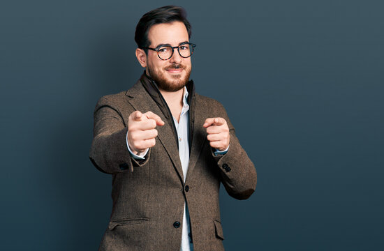 Young hispanic man wearing business jacket and glasses pointing fingers to camera with happy and funny face. good energy and vibes.