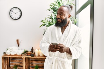 Young african american man smiling confident using smartphone at beauty center