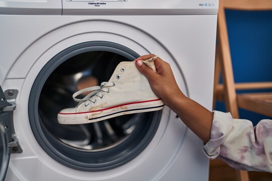 Young african american woman washing sneakers at laundry
