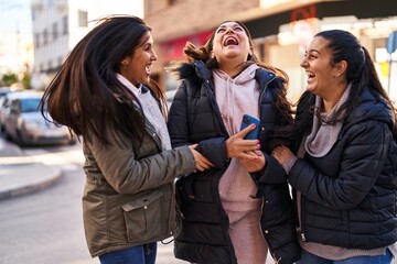 Three woman mother and daughters using smartphone at street