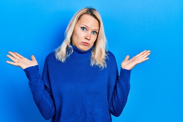 Beautiful caucasian blonde woman wearing turtleneck sweater clueless and confused with open arms, no idea and doubtful face.