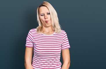 Young caucasian woman wearing casual clothes making fish face with lips, crazy and comical gesture. funny expression.