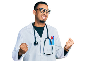 Young african american man wearing doctor uniform and stethoscope very happy and excited doing winner gesture with arms raised, smiling and screaming for success. celebration concept.