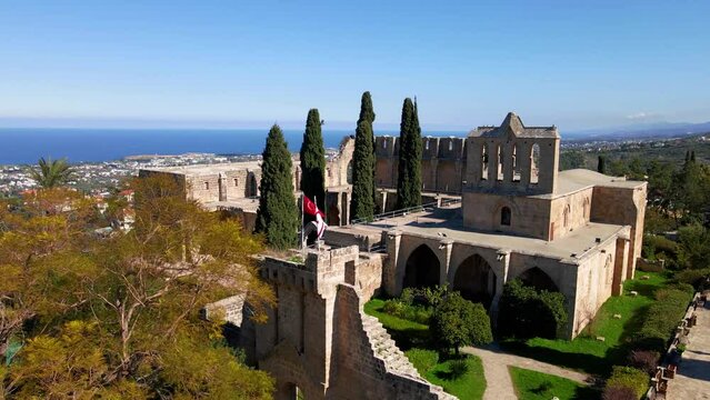 Aerial 4K view of beautiful Bellapais Village with Bellapais Monastery in Kyrenia, North Cyprus surrounded with an amazing green Mediterranean nature and picturesque landscapes in Cyprus.