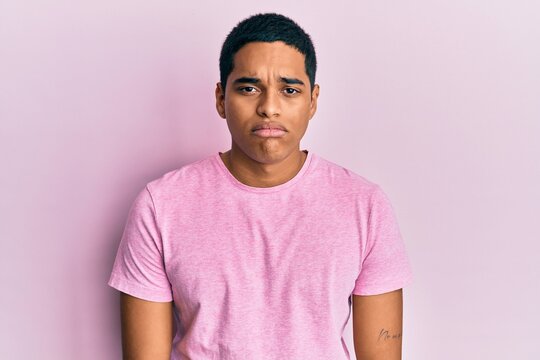 Young handsome hispanic man wearing casual pink t shirt depressed and worry for distress, crying angry and afraid. sad expression.