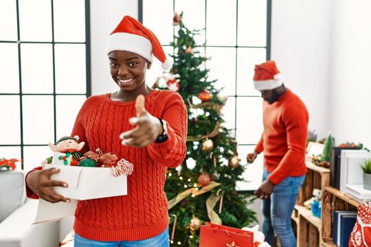 Young african american couple standing by christmas tree pointing fingers to camera with happy and funny face. good energy and vibes.
