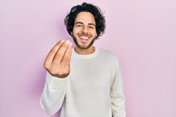 Fototapeta premium Handsome hispanic man wearing casual white sweater doing italian gesture with hand and fingers confident expression