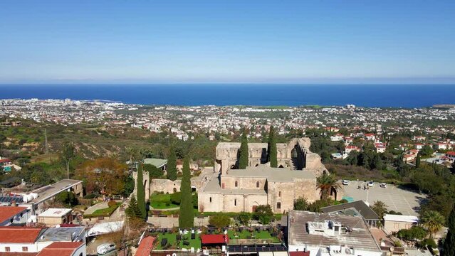 Aerial 4K view of beautiful Bellapais Village with Bellapais Monastery in Kyrenia, North Cyprus surrounded with an amazing green Mediterranean nature and picturesque landscapes in Cyprus.