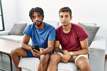 Young hispanic men using smartphone sitting on the sofa at home looking sleepy and tired, exhausted...