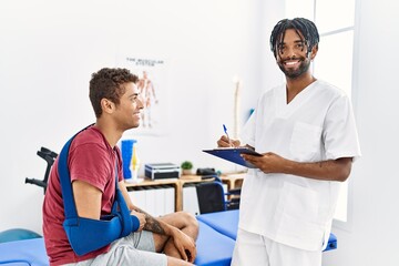 Obraz premium Two men physiptherapist and patient having rehab session writing accident report at clinic