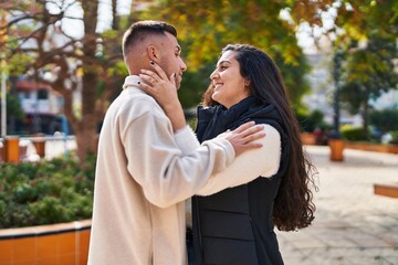 Man and woman couple hugging each other standing at park