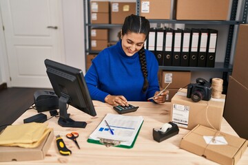 Young hispanic woman ecommerce business worker counting dollars at office