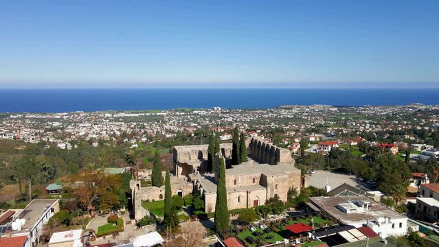 Aerial 4K view of beautiful Bellapais Village with Bellapais Monastery in Kyrenia, North Cyprus surrounded with an amazing green Mediterranean nature and picturesque landscapes in Cyprus.