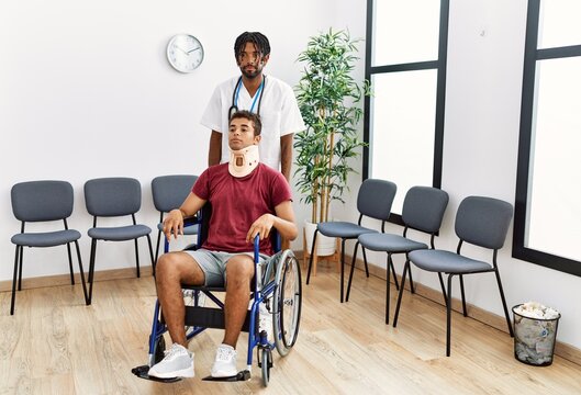 Two men physiptherapist and patient sitting on wheelchair having medical consultation at hospital waiting room