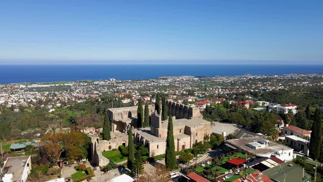 Aerial 4K view of beautiful Bellapais Village with Bellapais Monastery in Kyrenia, North Cyprus surrounded with an amazing green Mediterranean nature and picturesque landscapes in Cyprus.