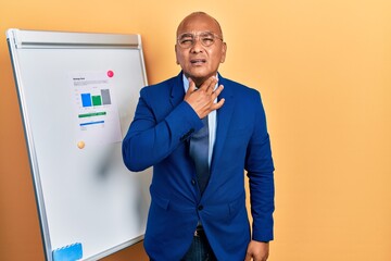 Middle age latin man wearing business clothes on chart presentation touching painful neck, sore throat for flu, clod and infection