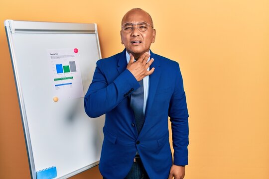 Middle age latin man wearing business clothes on chart presentation touching painful neck, sore throat for flu, clod and infection