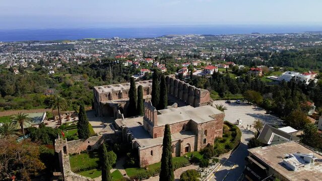 Aerial 4K view of beautiful Bellapais Village with Bellapais Monastery in Kyrenia, North Cyprus surrounded with an amazing green Mediterranean nature and picturesque landscapes in Cyprus.
