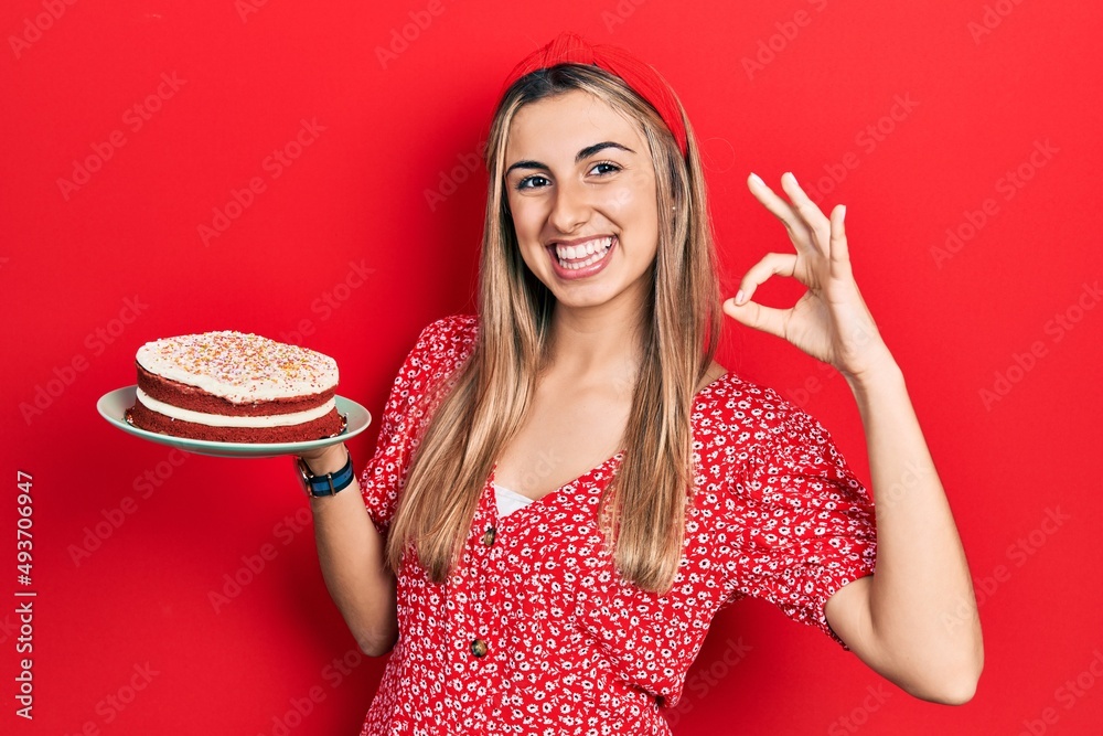 Sticker beautiful hispanic woman holding strawberry cake doing ok sign with fingers, smiling friendly gestur