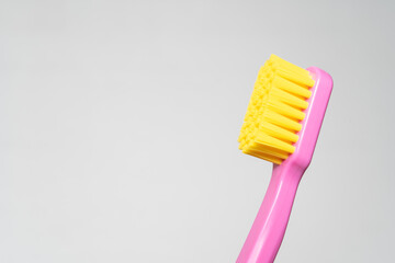 toothbrush with pink handle yellow brush head. Toothbrush closeup on white background.