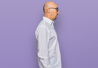 Fototapeta premium Bald man with beard wearing business shirt and glasses looking to side, relax profile pose with natural face with confident smile.
