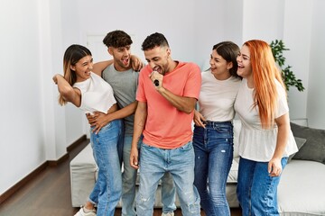 Fototapeta premium Group of young friends having party singing song using microphone at home.