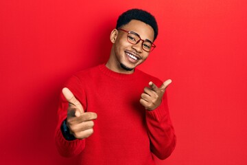Young african american man wearing casual clothes and glasses pointing fingers to camera with happy and funny face. good energy and vibes.