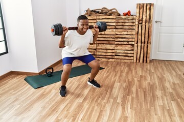 Fototapeta na wymiar Young african man training with dumbbells at the gym