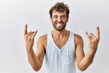 Young handsome man standing over isolated background shouting with crazy expression doing rock symbol with hands up. music star. heavy concept.